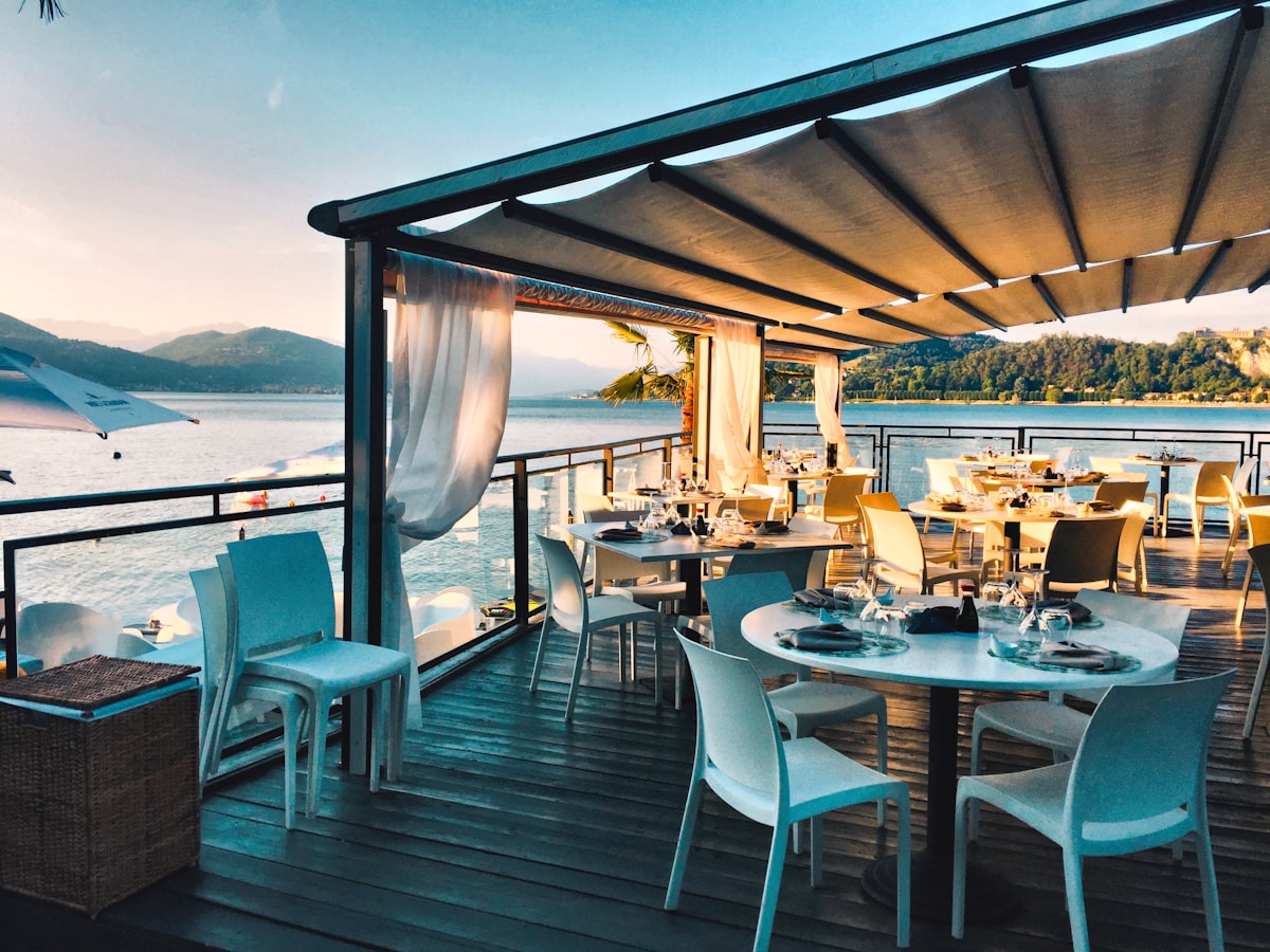 A bright waterfront restaurant terrace set for guests
